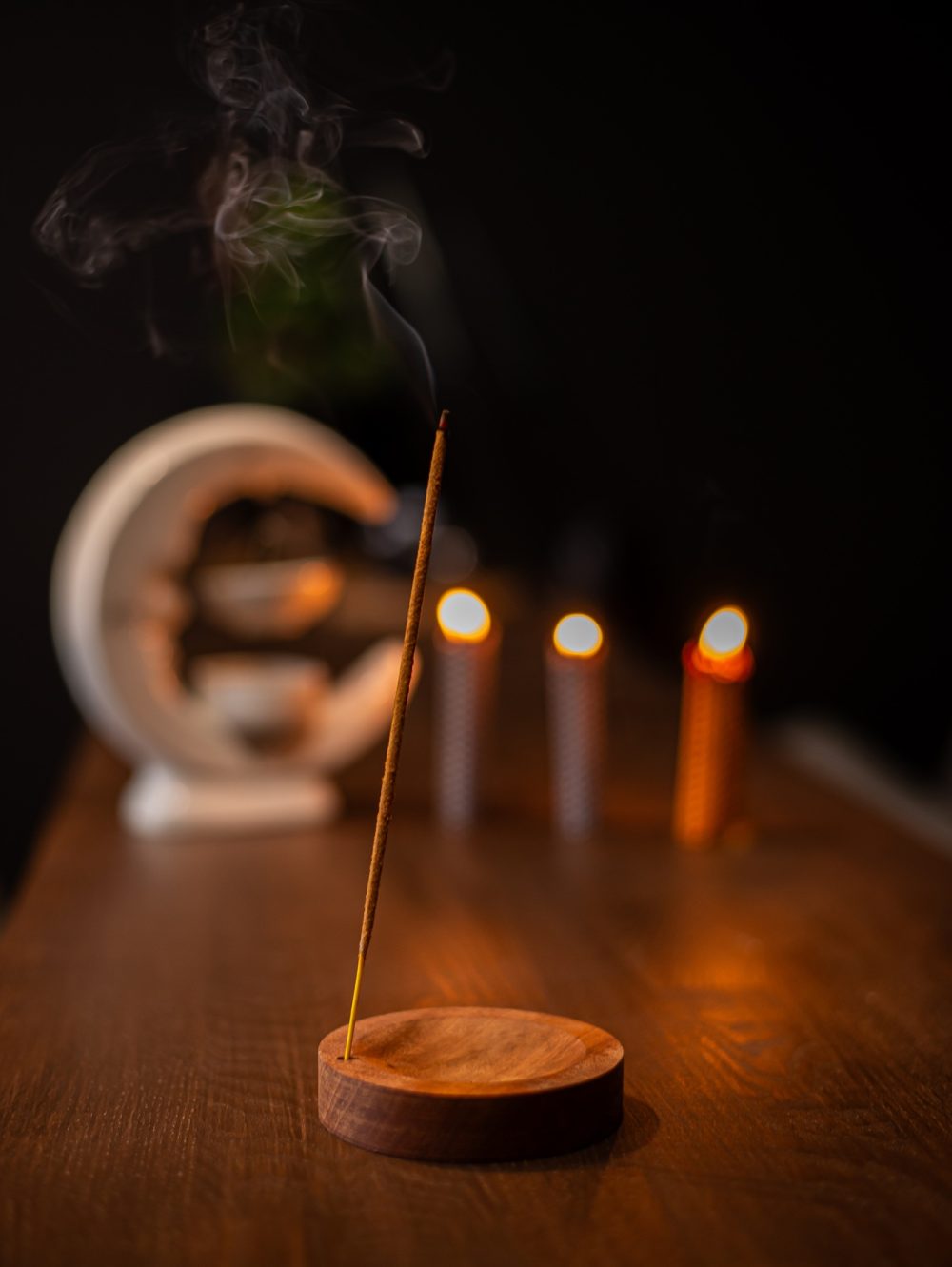 incense stick smokes on a wooden stand on a dark background. Aromatherapy, Smoke while burning